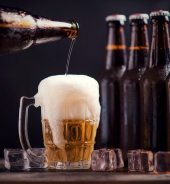 garrafas de vidro de cerveja com vidro e gelo no fundo escuro